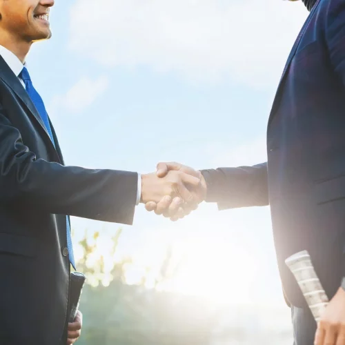 Business handshake Business handshake. Two businessmen shaking hands while standing outdoors holding tennis rackets. Men shaking hands during a meeting on outdoors background, success, dealing, greeting and partner.